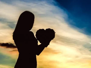 silhouette d'une femme tenant un objet en forme de coeur dans les mains